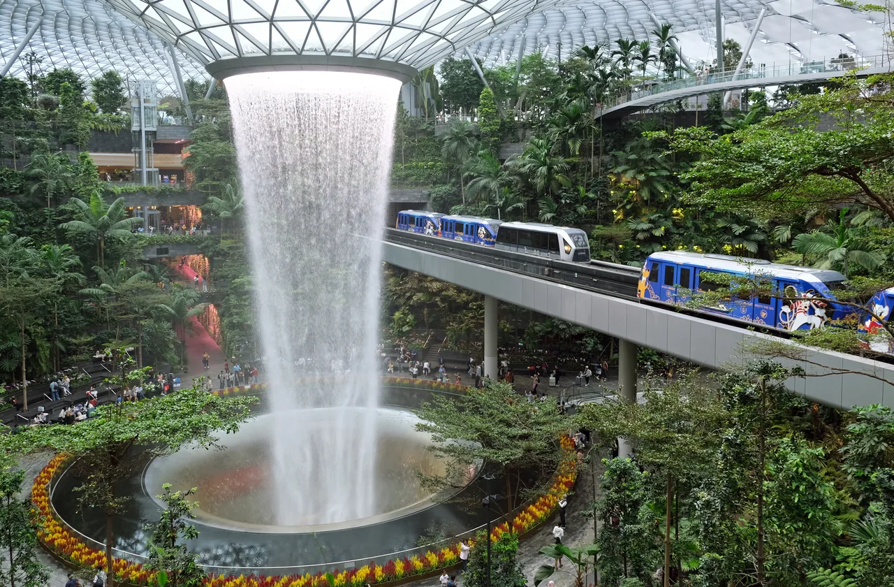 The Rain Vortex indoor waterfall at Jewel Changi Airport surrounded by greenery